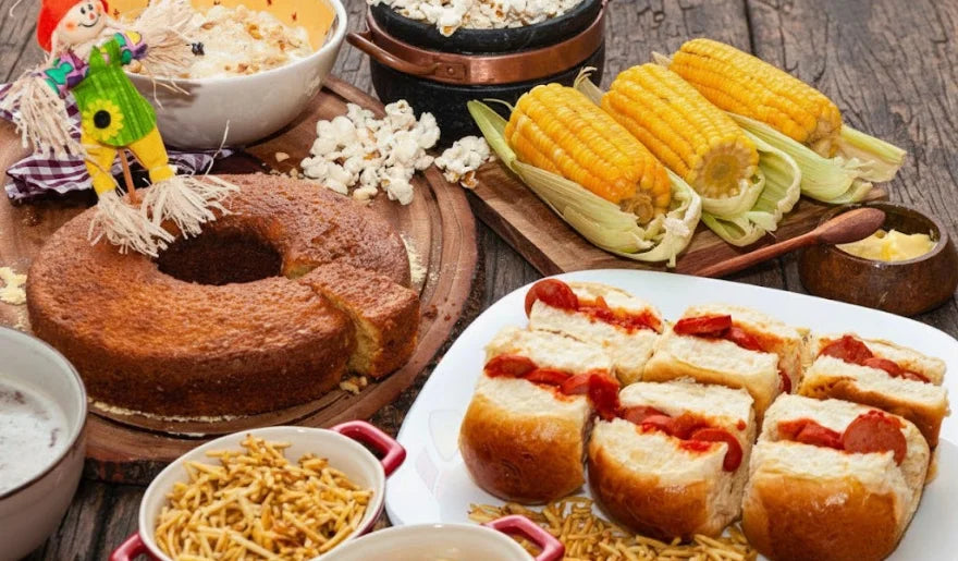 Uma imagem em close-up de vários doces de amendoim marrom-escuros, cobertos com açúcar, em forminhas de papel branco com babados, cada um com um amendoim inteiro por cima, dispostos sobre uma superfície de madeira escura.